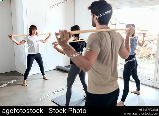 Instructor teaching stick yoga in health club