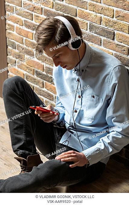 Young man wearing headphones and using phone