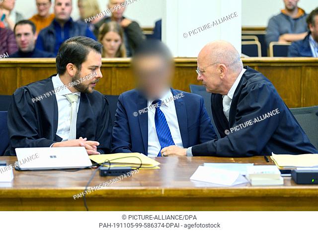 05 November 2019, Lower Saxony, Aurich: The defendant (M), former chief physician at Leer Hospital, sits between his lawyers Sebastian Wendt (l) and Christian...