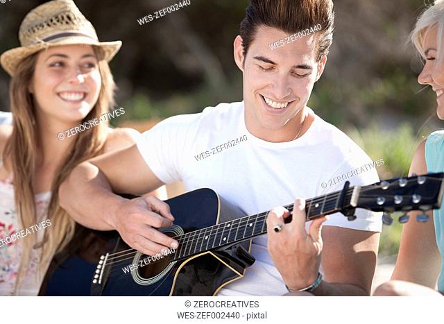 Happy friends with guitar outdoors
