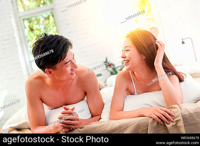 Happy young couple lying on the bed