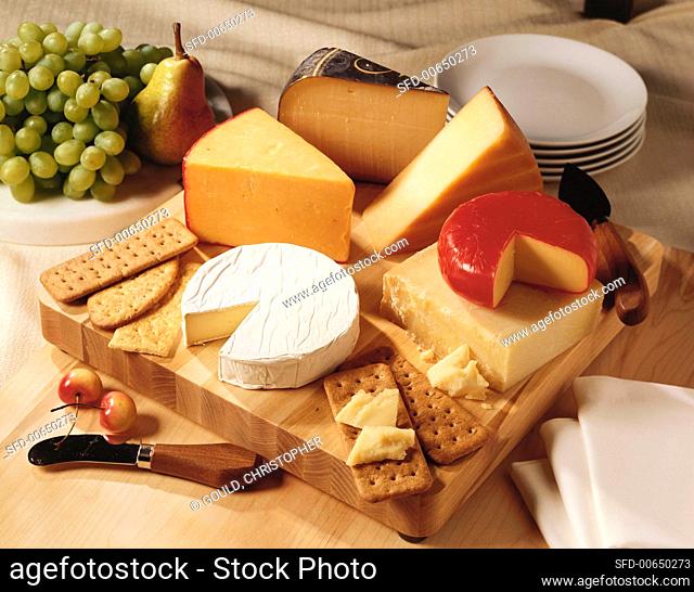 Cheese and crackers on a wooden board with fresh fruit