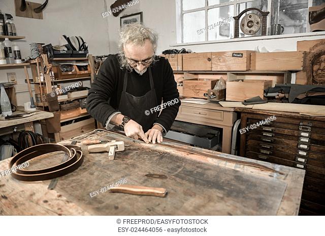 leather goods craftsman at work in his workshop, France