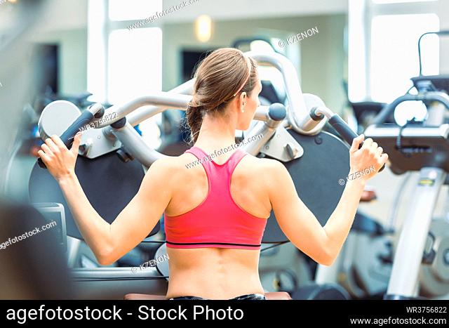 Side view of a determined and beautiful fit woman cycling on stationary bicycle during workout for burning calories at the gym