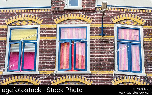 Anmcient windows in a Dutch house with colorful curtains