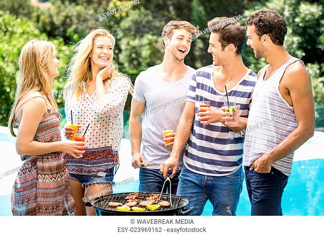 Group of happy friends preparing barbecue near pool