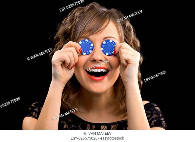 Young woman holding gambling chips in front of her eyes smiling