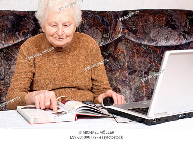 Oma mit Buch und Laptop