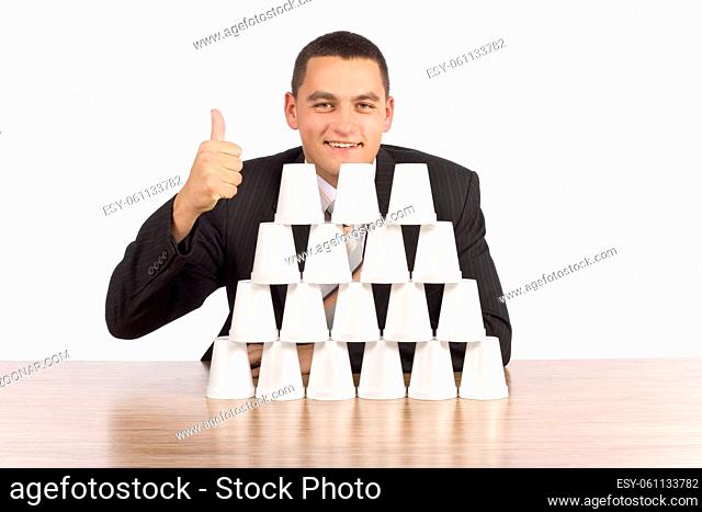 isolated on white businessman building cups' pyramid