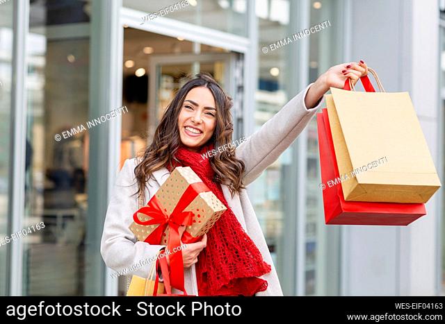 Happy young woman holding shopping bags with Christmas present