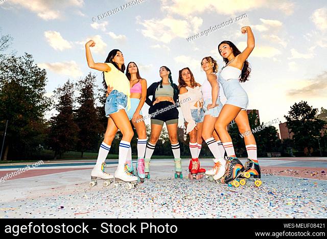 Women flexing muscles with friends standing at sports court