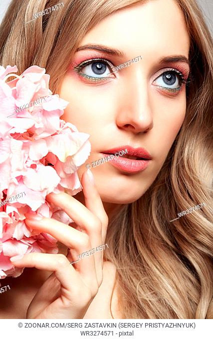 Closeup portrait of young beauty female face with blond hair and hydrangea bouquet flowers near face