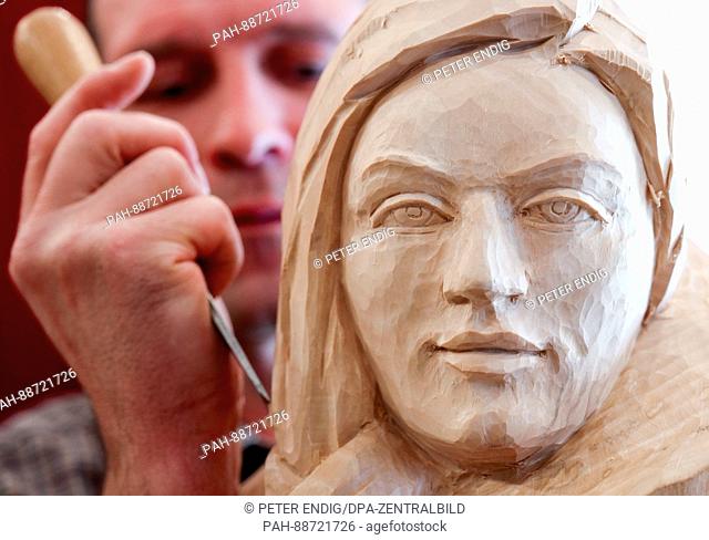 A man works on a carving of a woman's face in Anneberg-Buchholz, Germany, 04 March 2017. The town is hosting the 25th wood carving festival