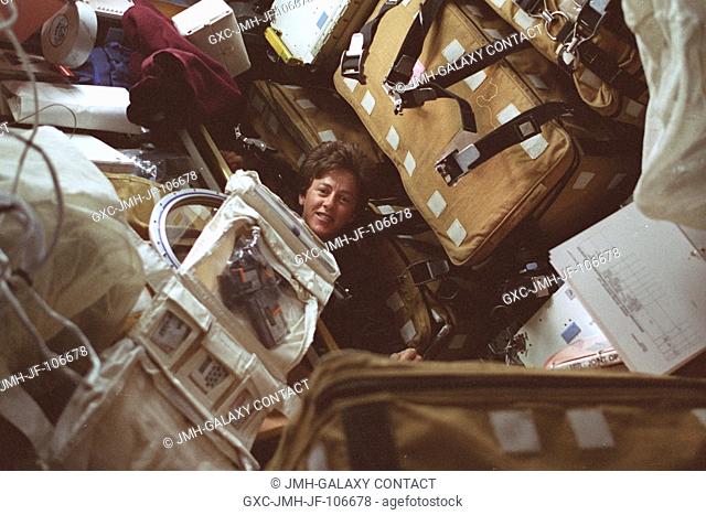 The face of astronaut Wendy B. Lawrence, STS-91 mission specialist, is almost lost amidst supplies and equipment yet to be transferred from the Space Shuttle...