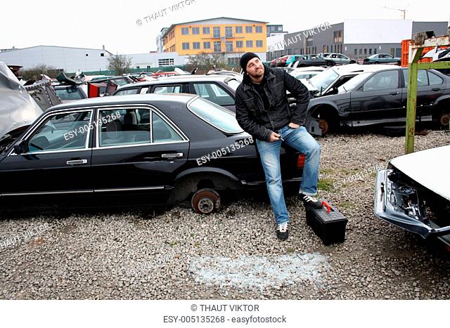 man looking at the scrap yard car parts