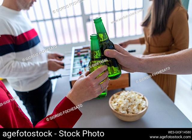 Colleagues toasting beer bottles in office