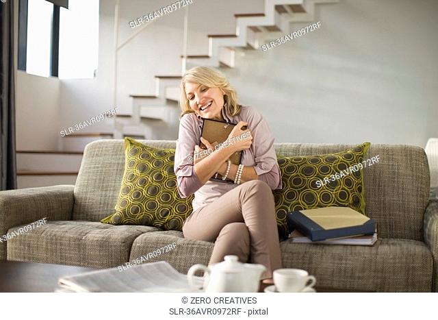 Woman hugging framed photo on couch