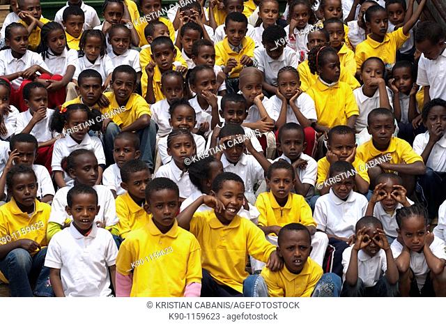 School class with young girls and boys in yellow and white shirts sitting on stairs, Addis Ababa, Ethiopia, East Africa