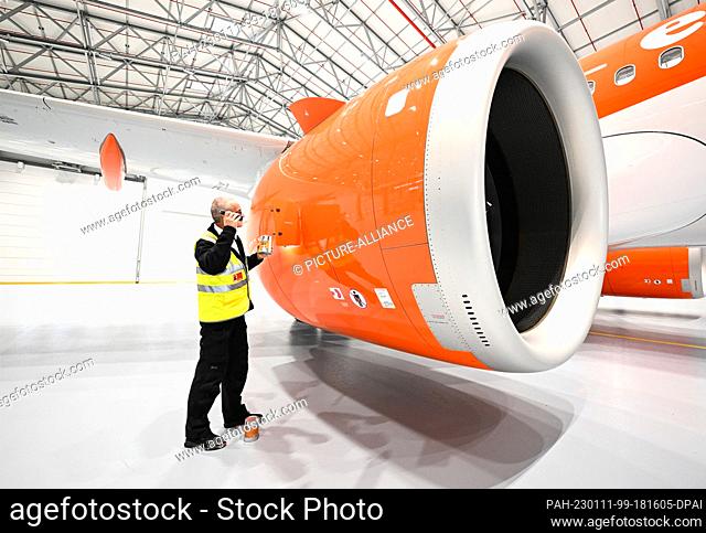 11 January 2023, Brandenburg, Schönefeld: Olaf Groß, Licence Engineer at easyJet, checks the oil level in the engine of an Airbus A320 Neo with a flashlight...