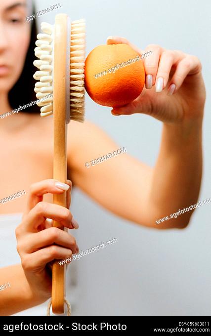 woman using Dry Brush for anti cellulite treatment. Woman using a natural fiber brush with a long handle for cellulite treatment. Skin body care