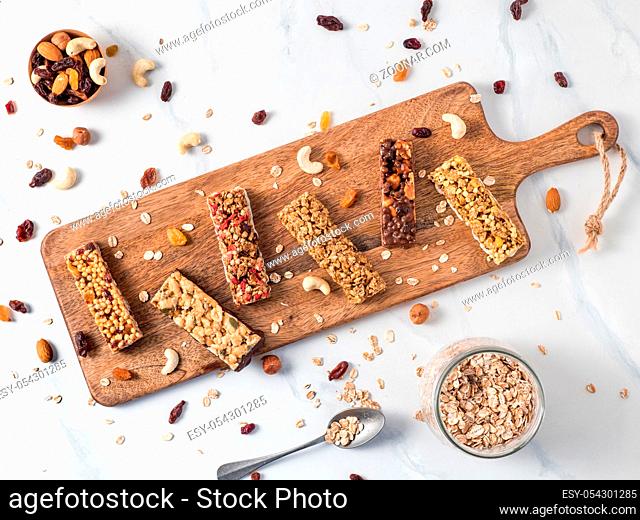 Granola bar with copy space. Set of different granola bars on cutting board over white marble table. Shallow DOF. Top view or flat lay
