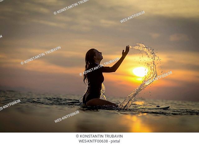 Indonesia, Bali, female surfer in the ocean at sunset
