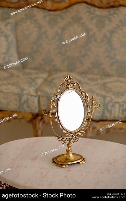 Closeup of vintage mirror represented on table in royal apartment. Royal golden frame on table in vintage interior