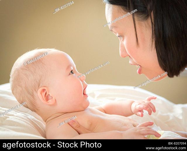 Young mixed-race chinese and caucasian baby boy laying in his bed with his mother