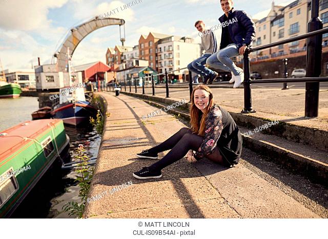Portrait of three friends sitting beside river, Bristol, UK