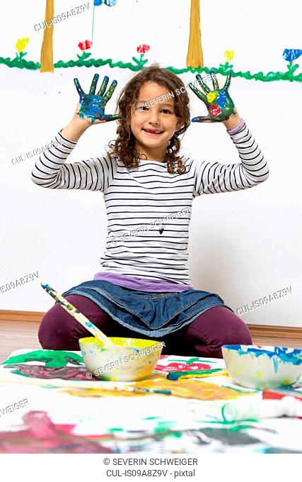 Girl kneeling on floor with painted hands