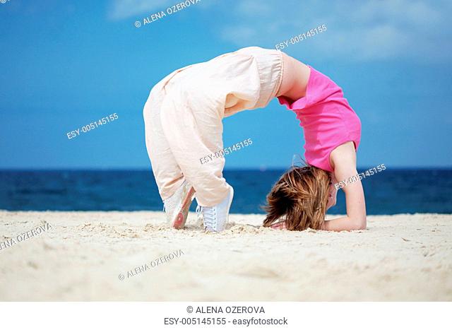 Teenage girl dancing hip-hop and jumping on beach, summer series