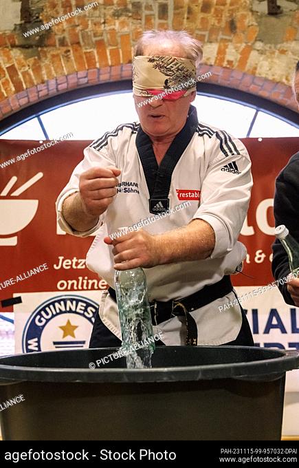 15 November 2023, Hamburg: Martial artist Muhamed Kahrimanovic in his Guinness record attempt ""Most glass bottles smashed blindly with a raw egg in his hand in...