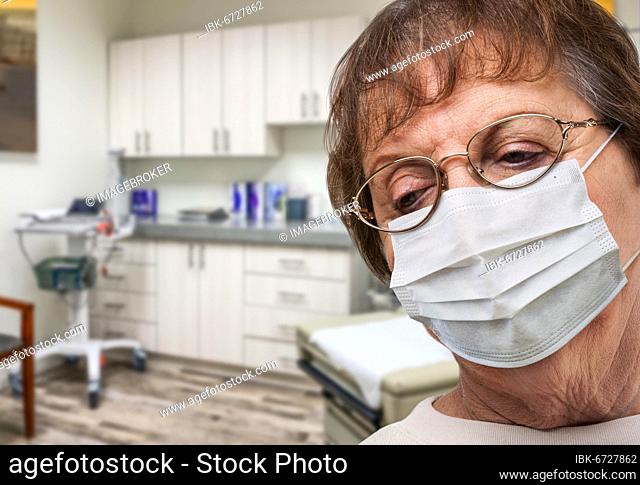 Concerned senior adult woman wearing medical face mask waiting in doctor office