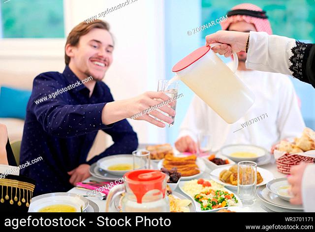Eid Mubarak Muslim family having Iftar dinner drinking water to break feast. Eating traditional food during Ramadan feasting month at home