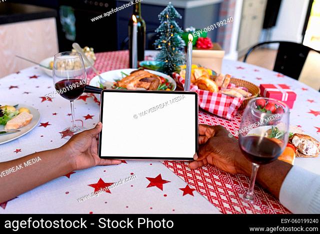Hands of african american senior couple using tablet with copy space at christmas time