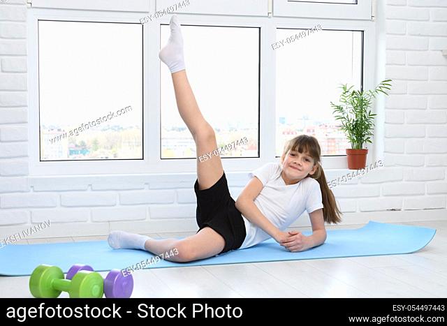 The girl lifted her leg up, doing morning exercises at home