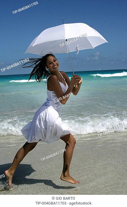 Woman running on beach with parasol