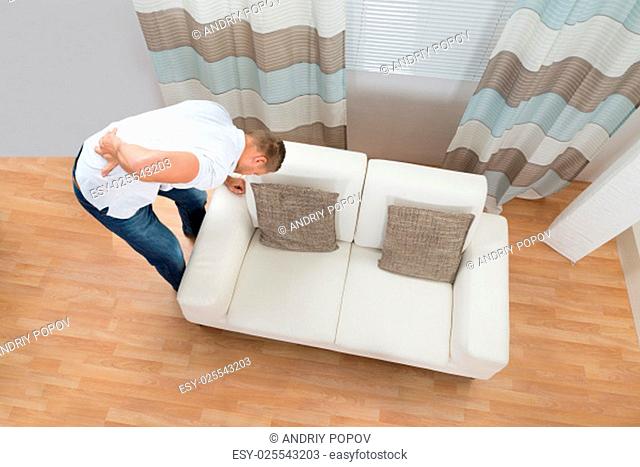 Young Man Standing Near Sofa Suffering From Back Pain