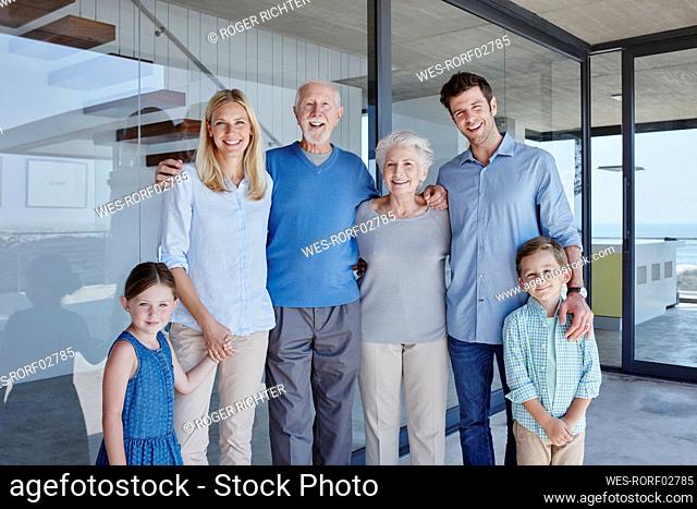Happy multi-generation family standing together in front of glass wall