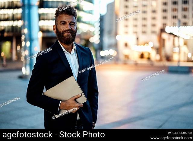 Smiling male freelance worker with beard holding digital tablet