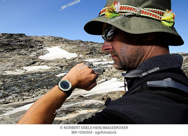 Man during an altitude check with a multifunction watch, hike, trekking in the Hundefjord, East Greenland, Greenland