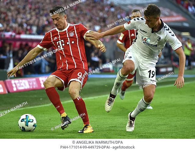 Bayern's Robert Lewandowski (l) and Freiburg's Janik Haberer vie for the ball during the German Bundesliga soccer match between Bayern Munich and SC Freiburg at...