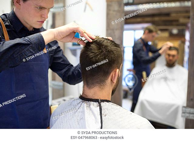 male hairdresser cutting hair at barbershop