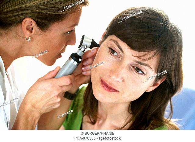Female doctor examining the ears of a female patient with an otoscope