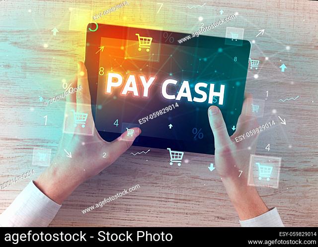 Close-up of a hand holding tablet with PAY CASH inscription, online shopping concept