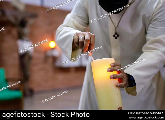 13 February 2022, Venezuela, Caracas: A priest lights a candle before a service in a church in the south of the city. Photo: Jesus Vargas/dpa