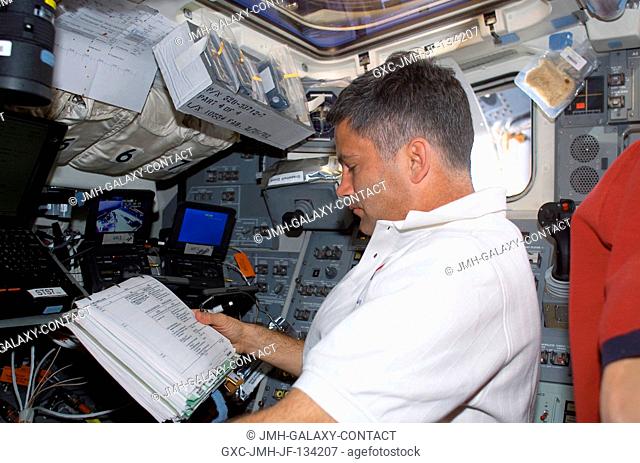 Astronaut Paul S. Lockhart, STS-113 pilot, looks over a procedures checklist on the aft flight deck of the Space Shuttle Endeavour