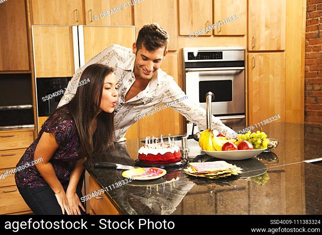 Woman blowing out birthday candles in kitchen