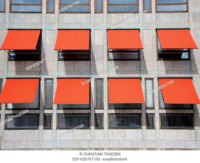 Red Overhang Sunshade Awning with shadows on Grey Building Facade Protecting from the Sun