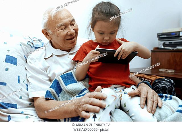 Grandfather and granddaughter with digital tablet at home